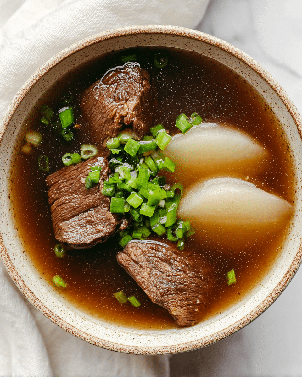 A close-up of a white spoon holding a piece of cooked brown beef topped with two small green onion slices, above a white bowl filled with clear brown broth that has visible green onion pieces and light beige potato slices. The bowl sits on a white marbled surface. photo taken with an iphone --ar 4:5 --v 7