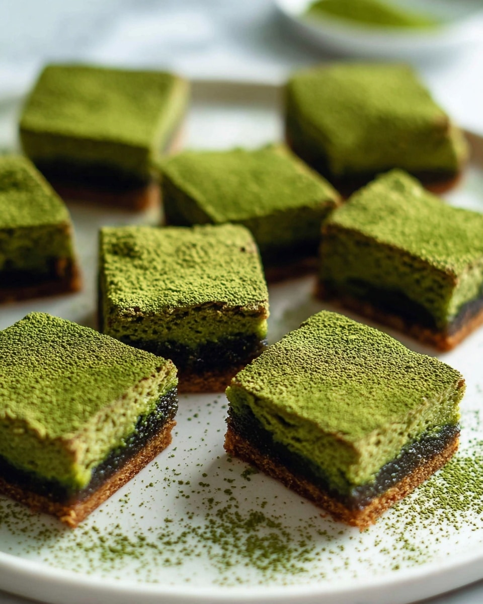 Several square pieces of green matcha brownies are arranged on a white plate resting on a white marbled surface. Each brownie has a dense, slightly crumbly texture with a dark brown layer at the bottom and a vibrant green top layer generously dusted with fine green matcha powder. The edges of the brownies are a darker golden brown, contrasting with the soft green and dark brown layers inside. Some matcha powder is scattered around the plate, adding a natural, rustic touch. Photo taken with an iphone --ar 4:5 --v 7
