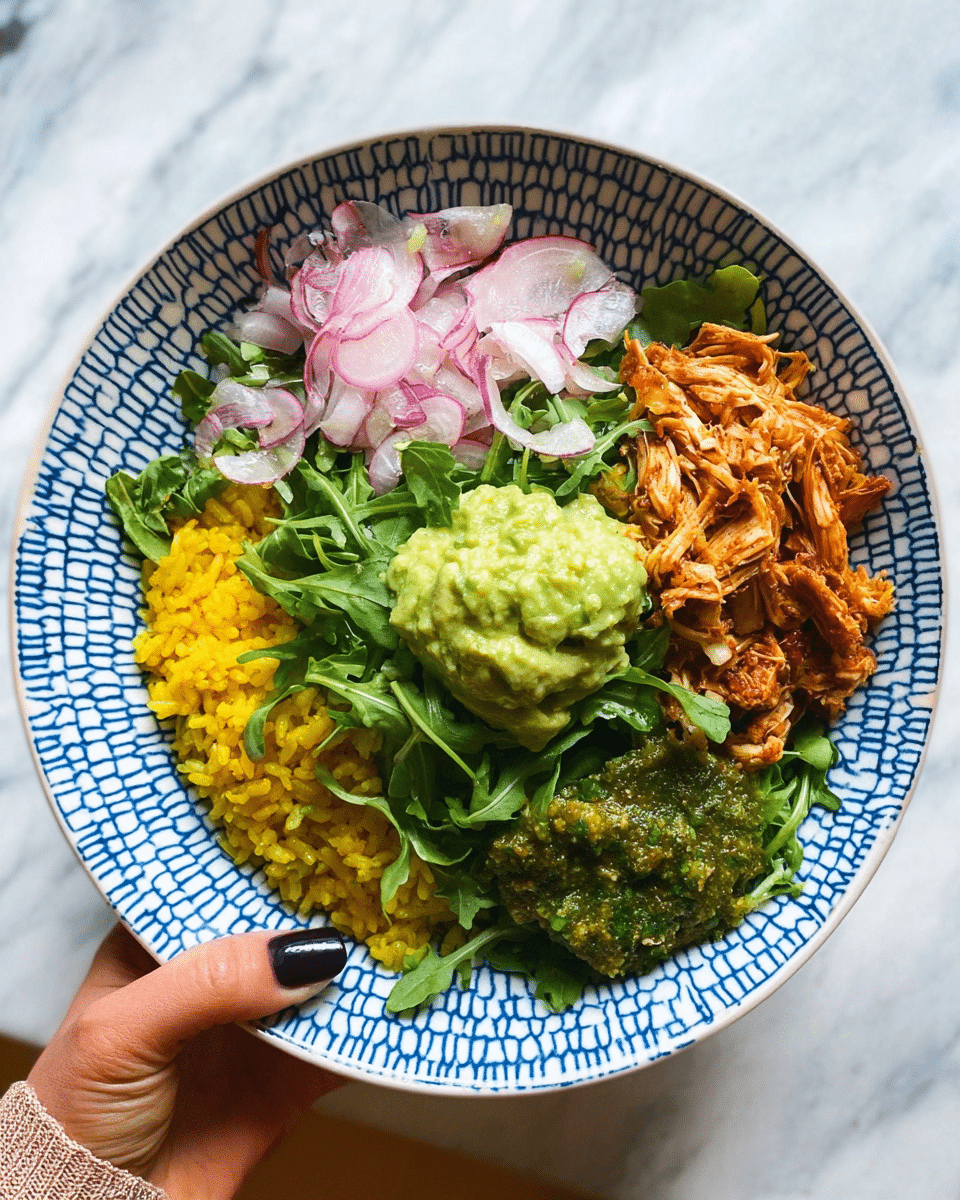 The dish is served in a white bowl with a blue geometric pattern, held by a woman's hand with dark nail polish. The bowl contains five visible layers arranged in a circular pattern: bright yellow rice at the bottom left, shredded reddish-brown cooked chicken on the bottom right, thinly sliced light pink onions on top of the chicken, fresh green leafy arugula mixed with thin slices of purple and white radishes on the upper half, and two dollops of sauces in the center—one light green smooth guacamole and the other a textured darker green pesto-like sauce. The whole image is set against a white marbled texture background. photo taken with an iphone --ar 4:5 --v 7