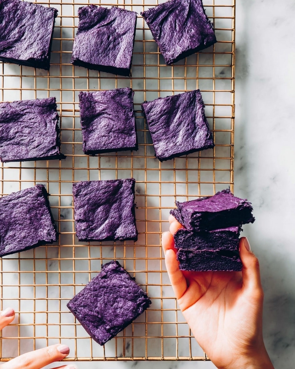 The image shows several purple square brownies with a wrinkled texture on top placed on a gold wire cooling rack over a white marbled surface. The brownies are evenly cut into single-layer squares with a consistent deep purple color throughout. In the bottom right, a woman's hand holds a stack of three brownies, clearly showing the soft, dense texture inside each piece. At the bottom left, another woman's hand rests lightly on the surface. The scene is bright and clean, emphasizing the vivid purple of the brownies. photo taken with an iphone --ar 4:5 --v 7