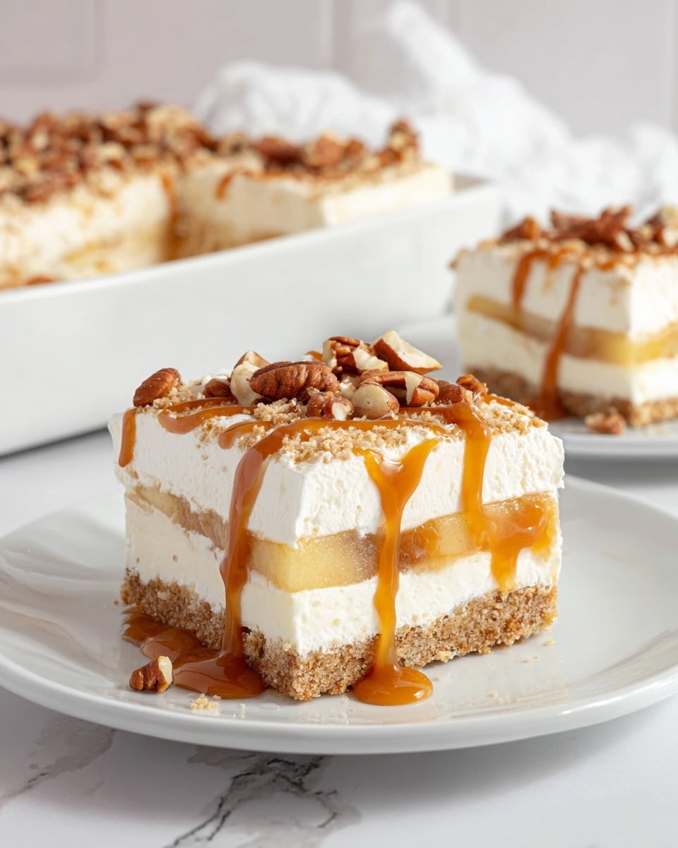 A white plate holds a square slice of dessert with four distinct layers: the bottom is a crumbly light brown crust, above it is a thick creamy white layer, followed by a translucent golden apple filling, and topped with a thick smooth white cream layer. The top cream layer is decorated with scattered brown pecan nuts and drizzled with glossy caramel sauce that drips slightly down the sides. In the background, a white dish filled with the same dessert and another white plate with a smaller piece are set on a white marbled surface. Photo taken with an iphone --ar 4:5 --v 7