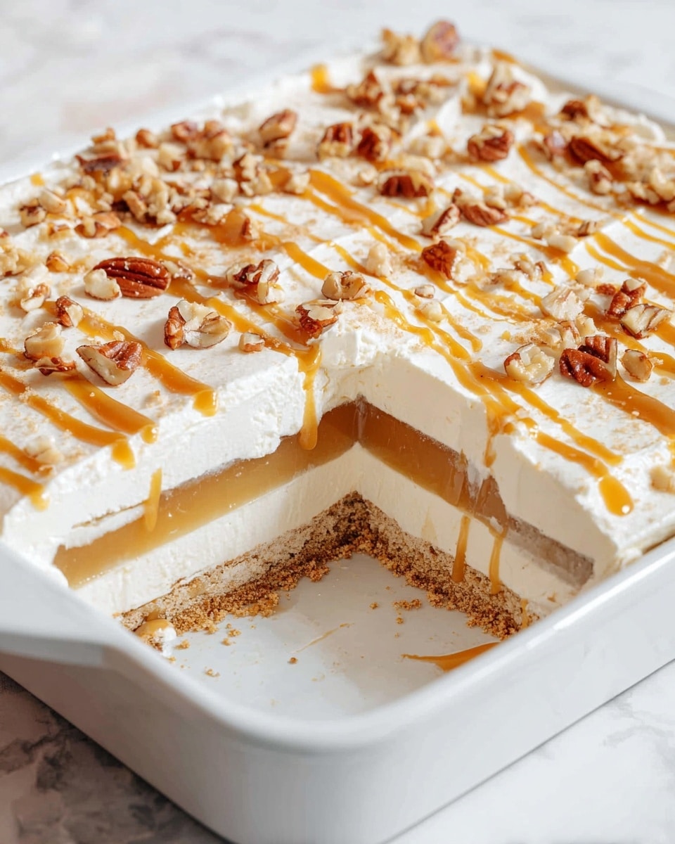 The image shows a square dessert with four visible layers in a white baking dish on a white marbled surface. The bottom layer is a crumbly, light brown crust. Above that is a thick, smooth cream layer in white. The next layer is a shiny, light caramel-colored jelly with visible swirls. The top layer is white, fluffy cream with diagonal drizzles of caramel sauce and scattered small pieces of chopped pecans, adding a textured look. One slice is missing, revealing the inside layers clearly. photo taken with an iphone --ar 4:5 --v 7