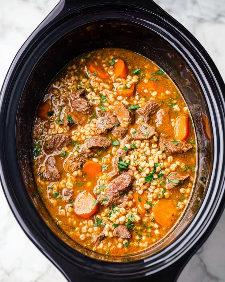 The image shows a black slow cooker filled with a thick stew. The stew has visible chunks of brown meat, soft orange carrot slices, and light-colored barley grains mixed together in a golden-brown broth. Small green herb pieces are sprinkled all over, adding a touch of color contrast. The slow cooker is placed on a white marbled surface, with the rich textured stew filling most of the visible space inside the cooker. photo taken with an iphone --ar 4:5 --v 7