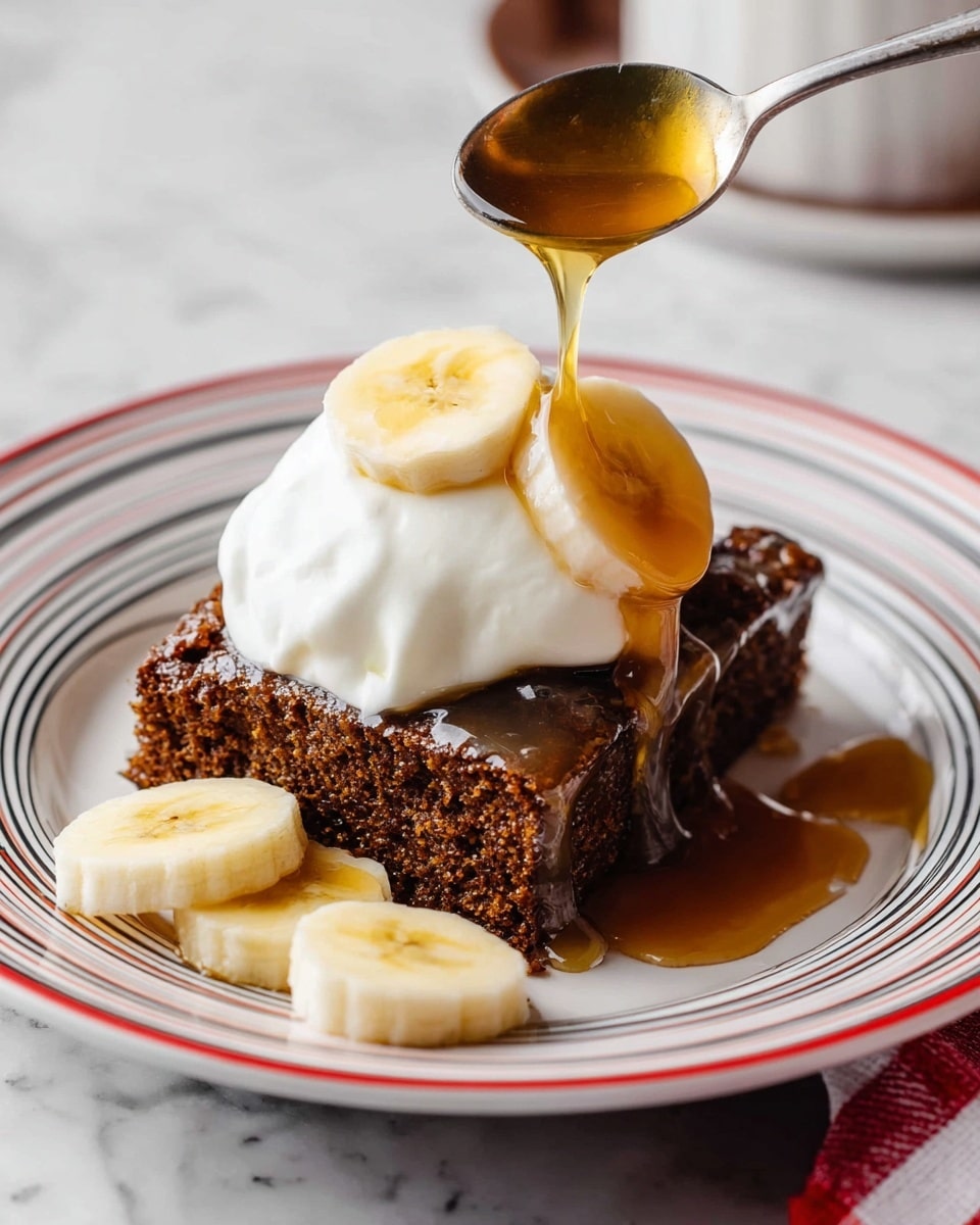 A square piece of dark brown cake with a rough texture sits on a white plate with red and black lines. On top of the cake is a thick, white dollop of whipped cream, crowned with two round banana slices. Golden syrup is being poured from a spoon above, flowing down the whipped cream and cake, adding a shiny glaze. On the plate, next to the cake, are three more banana slices showing their light yellow color and soft texture. The plate rests on a white marbled surface. photo taken with an iphone --ar 4:5 --v 7