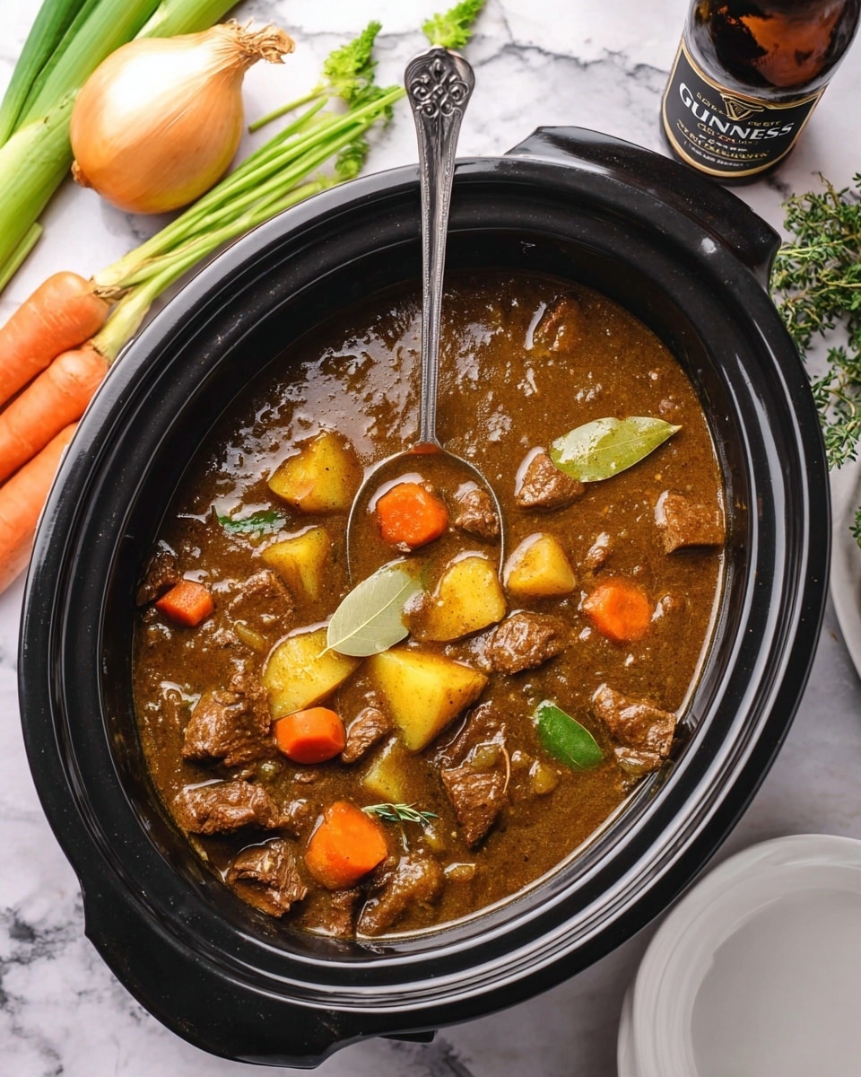 A black slow cooker filled with a thick brown stew, showing chunks of cooked beef, bright orange carrot slices, and yellow potato pieces mixed in a glossy, rich broth. The stew has a few visible green herbs and bay leaves floating on top, adding texture and color. A silver spoon is resting inside the slow cooker on the left side. Around the cooker are fresh ingredients including a whole white onion, an orange carrot, green celery stalks, and a dark brown bottle of Guinness beer lying on a white marbled surface. To the right, there is an empty white plate partially visible. photo taken with an iphone --ar 4:5 --v 7