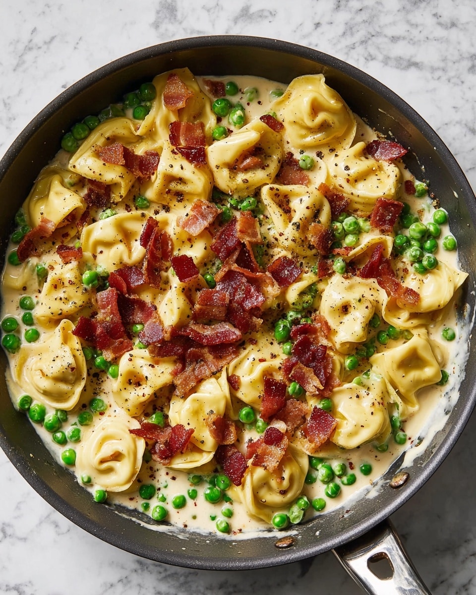 A dark pan filled with three layers: the bottom layer is a creamy white sauce with a smooth texture, middle layer has small bright green peas scattered all over, and the top layer shows light yellow tortellini pasta folded into small pockets mixed with crispy reddish-brown bacon pieces, all lightly sprinkled with black pepper. The pan is placed on a white marbled surface with a silver handle on the right side photo taken with an iphone --ar 4:5 --v 7