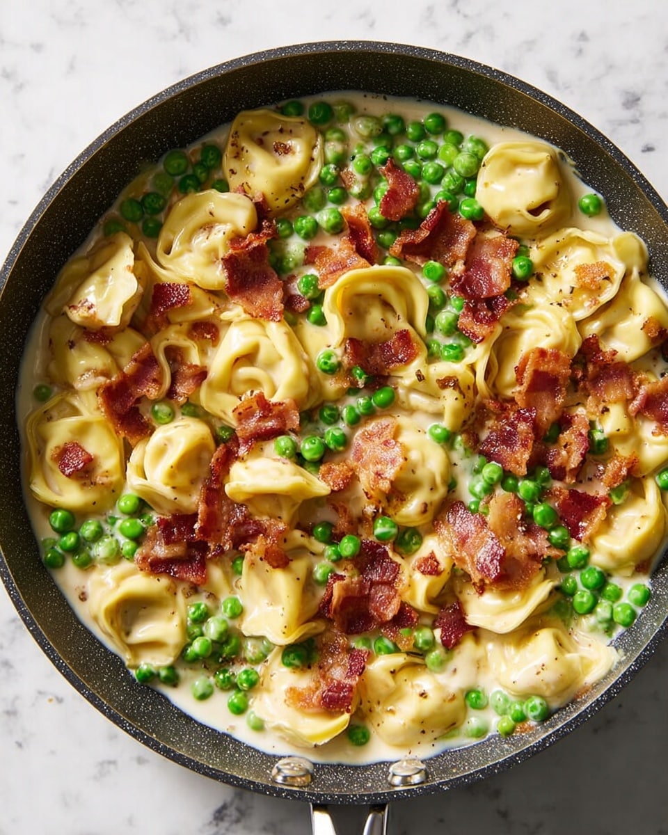 A close-up view of a dark frying pan filled with three main layers: the bottom layer is a creamy white sauce with a smooth texture, covering the whole pan base; on top of that, a layer of bright green peas is evenly spread, adding a fresh pop of color; the top layer consists of light yellow tortellini pasta stuffed and shaped in small rings, mixed throughout the pan, and sprinkled with crispy, reddish-brown pieces of cooked bacon, creating a contrast of soft and crunchy textures. The pan is placed on a white marbled surface. photo taken with an iphone --ar 4:5 --v 7