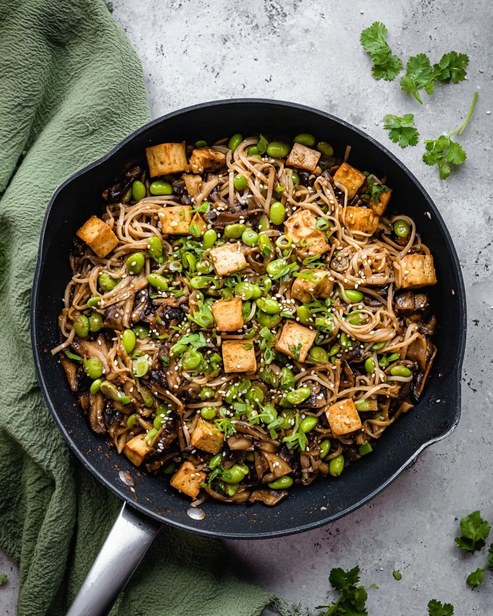 A bowl filled with three main layers: at the bottom, light brown flat rice noodles; scattered through the middle are golden-brown tofu cubes with a slightly crispy texture; and on top, bright green edamame beans, chopped green onions, and fresh green cilantro leaves, sprinkled with white sesame seeds. A fork rests inside the bowl, slightly digging into the noodles and tofu. The bowl is white and set on a white marbled surface, with small spices scattered around and a hint of a green cloth visible at the lower left. photo taken with an iphone --ar 4:5 --v 7