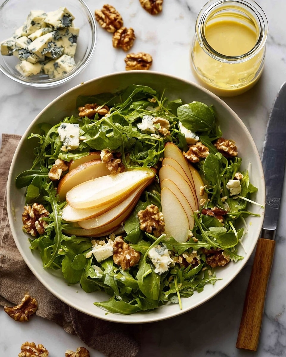 The image shows a white bowl filled with fresh arugula leaves as the bottom layer, topped with thin slices of light brown pear that have a smooth texture. Scattered on top are medium-sized pieces of blue cheese, creamy white with dark blue-green veins, and crunchy brown walnut halves. The whole setup is placed on a white marbled surface with a small glass bowl of blue cheese, pear slices, a knife with a wooden handle, and some loose walnuts around the bowl. A jar of light yellow dressing is visible behind the bowl. Photo taken with an iphone --ar 4:5 --v 7