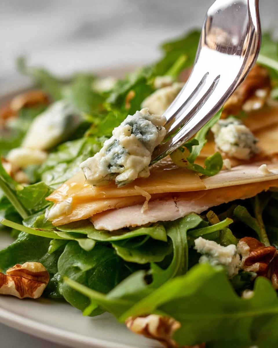 The image shows a close-up of a fresh salad on a white plate with layers of green arugula leaves at the bottom, followed by thin slices of light brown turkey or chicken breast layered on top. Small pieces of creamy blue cheese with blue veins are scattered across the top layer, along with a few pieces of brown walnuts. A silver fork is lifting some arugula, blue cheese, and turkey, focusing on the fresh textures and colors of the ingredients. The background is blurred with a white marbled texture. photo taken with an iphone --ar 4:5 --v 7