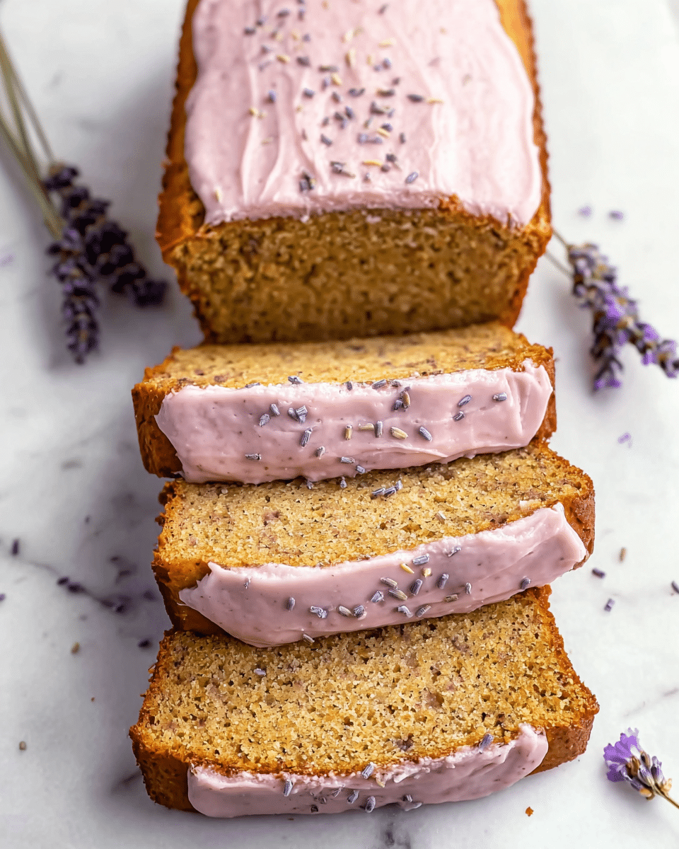 A loaf cake with three visible layers, each slice showing a dense, light brown crumb with tiny dark specks, suggesting a textured, moist interior. Between the slices and spread on top is a smooth, pale pink frosting dotted with small dark lavender sprinkles. The cake edges are golden brown, and the top layer of frosting looks thick and creamy with a slightly uneven spread. The whole cake rests on a white marbled surface with a few sprigs of lavender placed beside it. Photo taken with an iphone --ar 4:5 --v 7