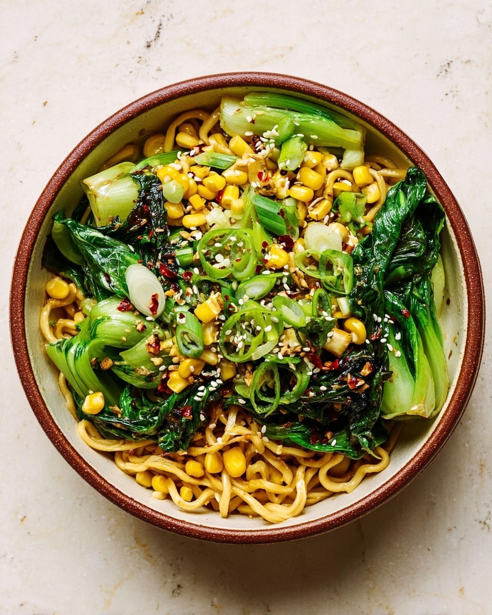 A round bowl with a brown rim holds a colorful noodle dish on a white marbled surface. The bottom layer is light yellow curly noodles mixed with small pale yellow corn kernels. Above that are bright green bok choy pieces and dark green leafy vegetables scattered throughout. The dish is garnished with sliced light green scallions and white sesame seeds sprinkled evenly on top. Small dark red chili flakes add bright spots of color, contrasting with the fresh greens and yellow corn. The dish looks warm and fresh. photo taken with an iphone --ar 4:5 --v 7