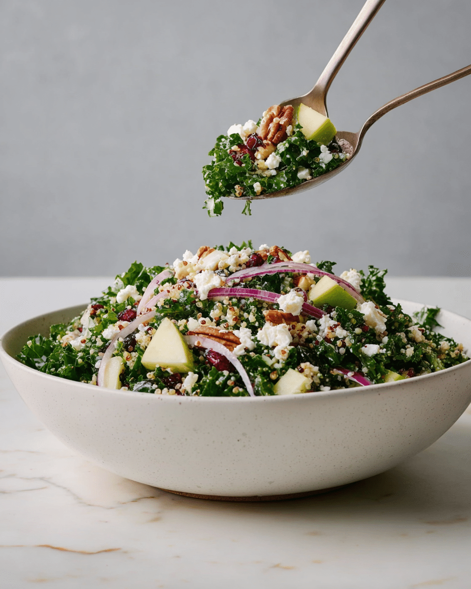 A large white bowl filled with a fresh salad showing multiple layers: the base is dark green curly kale leaves, mixed with small pieces of light green apple and thin slices of purple onion spread throughout. On top, there are white crumbles of cheese and small brown nuts, possibly pecans, scattered evenly. Some red dried cranberries and bits of quinoa mixed in add texture and color. A fork holds a serving above the bowl with a small apple piece, kale leaf, cheese crumb, and a nut clearly visible. The bowl sits on a white marbled surface with a plain light gray background. Photo taken with an iphone --ar 4:5 --v 7