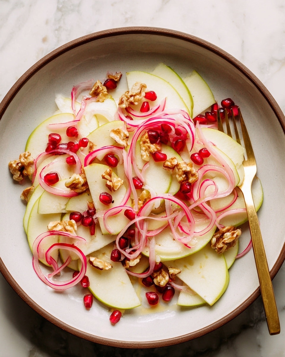 This dish is a fresh salad served on a white round plate with a brown rim, placed on a white marbled surface. The salad has thin, differently shaped slices of green apple and red radish layered evenly on the plate, creating a light green and white base with hints of red edges. Scattered above are curled light pink onion slices, adding a soft translucent texture and color. Small clusters of bright red pomegranate seeds are sprinkled across the top, along with pieces of toasted brown walnuts, providing a rough and crunchy contrast. A shiny gold fork rests on the right side of the plate. Photo taken with an iphone --ar 4:5 --v 7