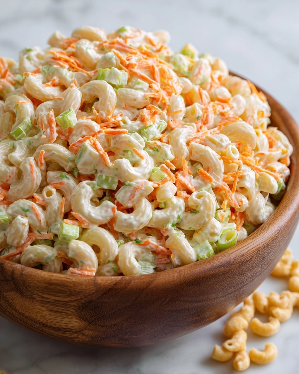 A close-up view of a large wooden bowl filled with creamy macaroni salad, showing three main layers: the base layer of curved, pale yellow macaroni pasta, the middle layer of finely chopped light green celery pieces mixed evenly, and the top layer with thin, grated orange carrot strips scattered throughout, all coated in a glossy, smooth white mayonnaise dressing that gives a shiny texture. The bowl sits on a white marbled surface with a few macaroni pieces scattered around for a natural look. photo taken with an iphone --ar 4:5 --v 7