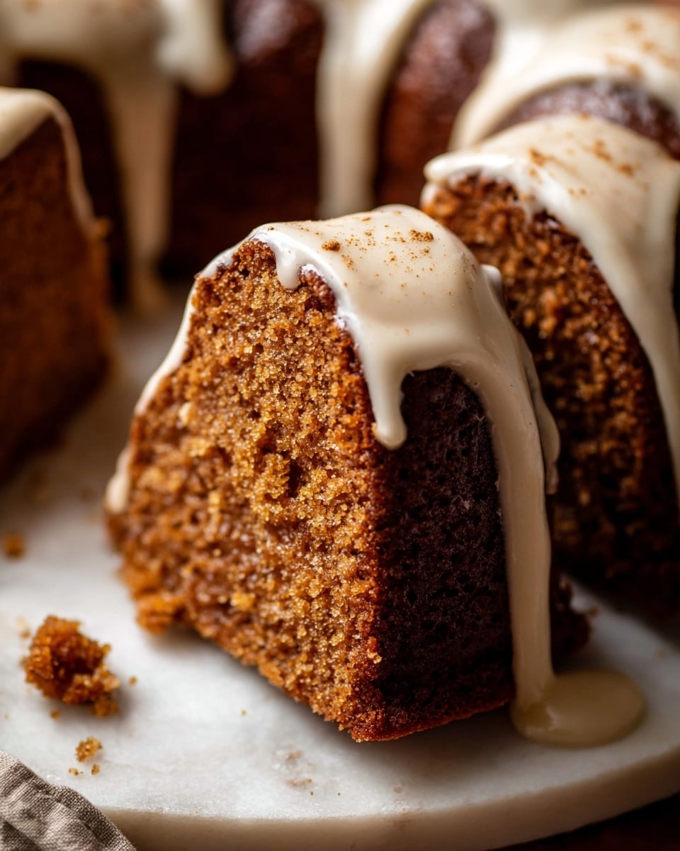A close-up view of a single thick slice of moist brown cake with a slightly crumbly texture, topped with a smooth, creamy off-white glaze that drips down the sides. The slice is part of a larger round cake with several similar slices, all covered with the same glaze that has a few small spots of brown sprinkle on top. The cake sits on a white plate with a white marbled texture surface underneath. A small crumb lies near the plate, adding a natural touch. photo taken with an iphone --ar 4:5 --v 7