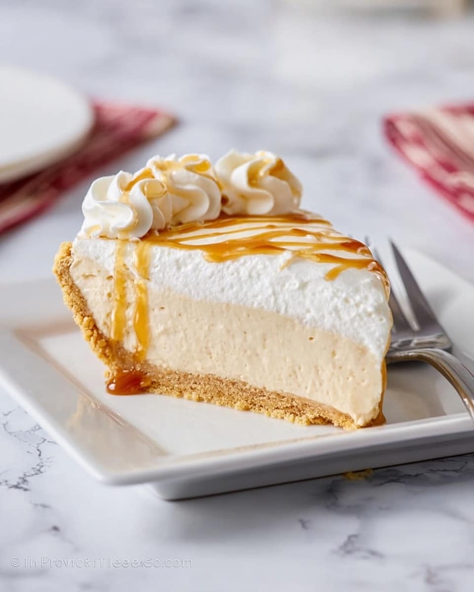 A slice of creamy pie is shown on a white square plate, resting on a white marbled surface. The pie has three distinct layers: a golden brown crust at the bottom, a thick middle layer of smooth, light beige filling, and a layer of white whipped cream on top, decorated with swirls. There is a light drizzle of caramel sauce over the whipped cream on the right side. A silver fork lies next to the plate, partially visible. Photo taken with an iphone --ar 4:5 --v 7
