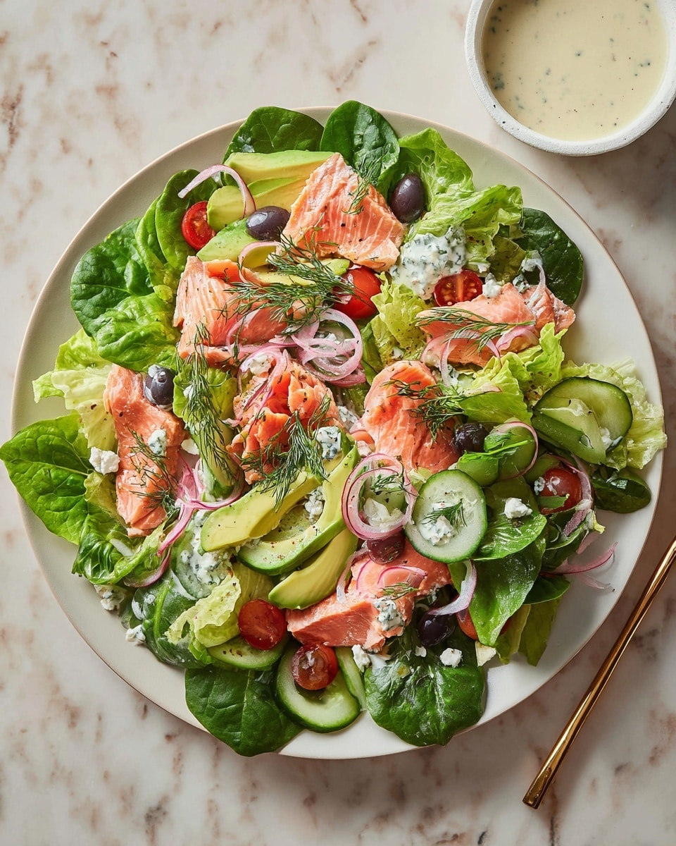 A white plate holds a fresh salad arranged in many layers. The base layer is bright green lettuce and dark green spinach leaves spread across the plate. On top, there are pale pink slices of salmon scattered unevenly, garnished with small dill sprigs. Thin slices of light green cucumber and pale green avocado are placed around and between the salmon. Cherry tomato halves add bright red spots, while black olive halves provide dark contrast. Thinly sliced pink pickled onions and small chunks of white feta cheese are sprinkled throughout the salad. The plate sits on a white marbled surface, and to the side is a small white bowl filled with a creamy dressing. Photo taken with an iphone --ar 4:5 --v 7