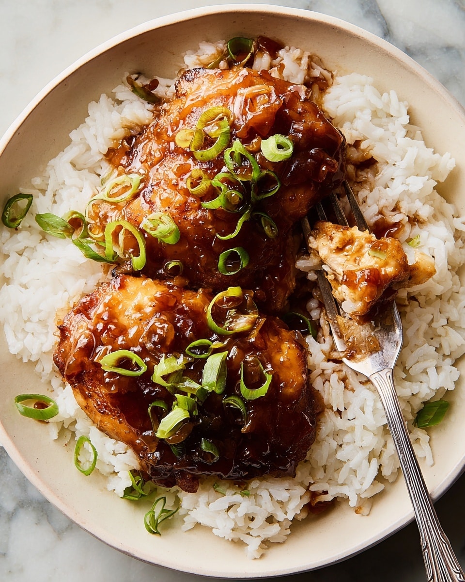The image shows a white plate filled with white steamed rice as the base layer, with two pieces of glazed chicken thighs placed on top. The chicken is coated in a shiny, thick brown sauce that looks sticky and flavorful. Bright green sliced scallions are sprinkled on the chicken, adding color contrast. A silver fork is on the plate, catching a portion of rice with sauce. The plate sits on a white marbled surface. photo taken with an iphone --ar 4:5 --v 7