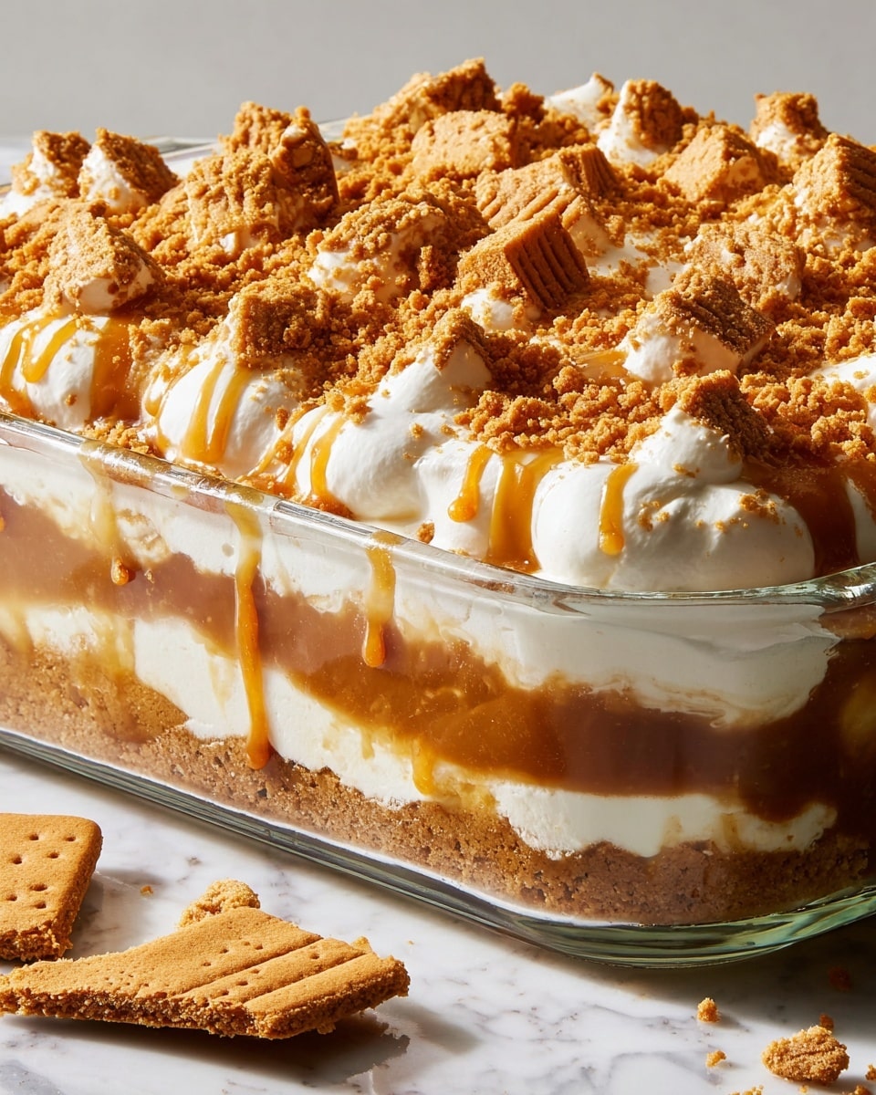 The dessert is in a clear glass dish showing four visible layers: the bottom layer is a crumbly, golden brown crust, above it is a smooth caramel layer with a rich, shiny texture, followed by a thick white creamy layer with soft peaks evenly spaced on top, and the top layer is drizzled with caramel sauce and sprinkled with chunky golden brown cookie crumbs. A broken golden brown cookie piece is placed on the white marbled surface beside the dish. The light highlights the creamy peaks and shiny caramel drizzle, making the dessert look soft and sweet. Photo taken with an iphone --ar 4:5 --v 7