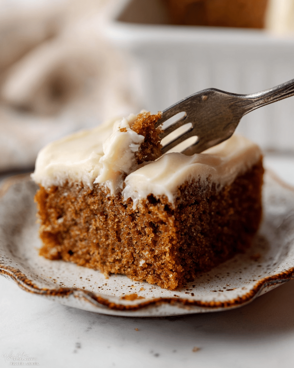 A close-up of a single square piece of soft brown cake with a moist, crumbly texture, topped with a thick, smooth layer of creamy white frosting that has a lightly speckled surface. The cake sits on a white plate with a rustic brown speckled and wavy edge. A silver fork is cutting into the cake from the right side, lifting a small piece of cake with frosting, showing the thick frosting layer covering the entire top. The background is softly blurred with a white marbled texture. photo taken with an iphone --ar 4:5 --v 7