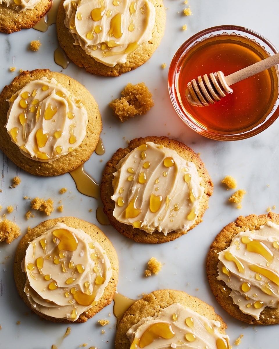 Several round warm cookies with a golden brown color form the bottom layer, each topped with a smooth, creamy light beige frosting spread evenly as the middle layer. The top layer consists of shiny, amber honey droplets drizzled over the frosting, adding a glossy texture. The cookies are casually placed on a white marbled surface with visible crumbs and small honey spills around, alongside a small clear glass bowl filled with golden honey and a honey dipper resting inside. Photo taken with an iphone --ar 4:5 --v 7