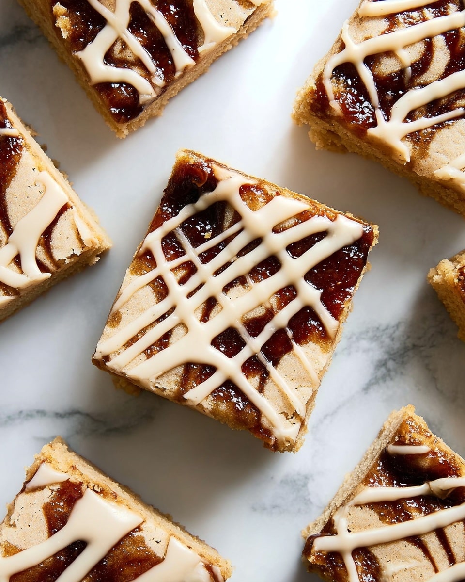 The image shows close-up squares of a dessert with two visible layers, placed on a white marbled surface. The base layer is a light brown, soft cake with a slightly crumbly texture. On top, there is a dark brown swirl pattern that looks like a sticky sauce or jam unevenly spread, giving a marbled effect. Over the swirls, there is a pale, creamy icing drizzled in thin, irregular lines crossing each other across the top, creating a contrast with the darker swirls below. The dessert squares are cut cleanly with sharp edges and arranged neatly with some spacing between them. photo taken with an iphone --ar 4:5 --v 7