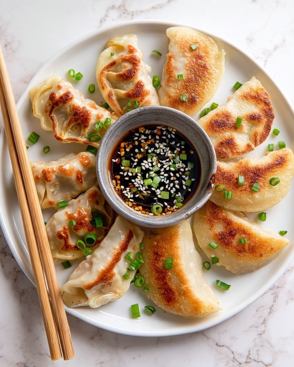 A white plate on a white marbled surface holds a group of six golden-brown pan-fried dumplings with crispy edges scattered with small bright green chopped scallions. On the upper left side of the plate is a small grayish-brown ceramic bowl filled with a light brown dipping sauce topped with chopped green scallions and white sesame seeds. The dumplings have a slightly shiny, soft texture with browned spots showing the roasting, and the sauce adds a colorful contrast. In the blurred background, there is a glimpse of chopsticks and another plate with more dumplings. Photo taken with an iphone --ar 4:5 --v 7