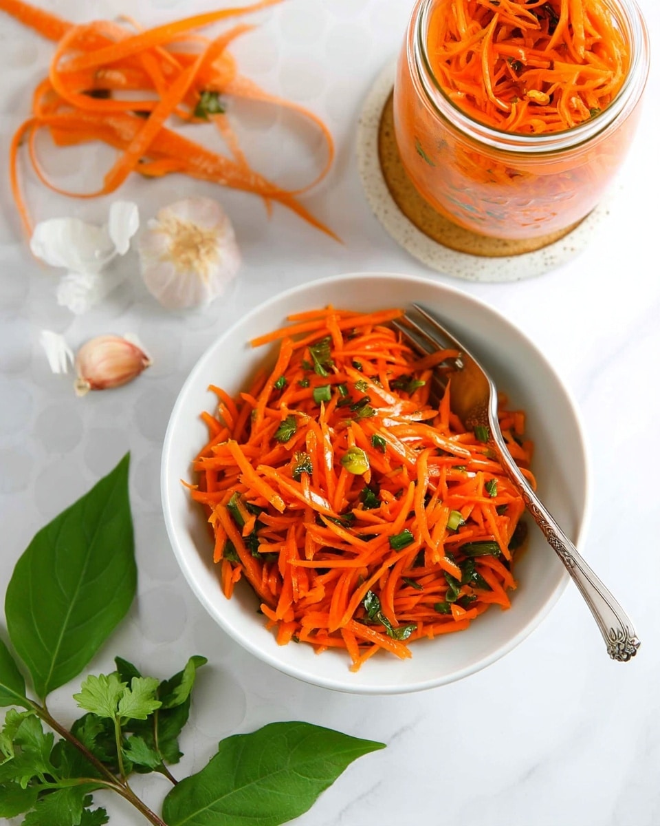 A white bowl filled with thin, bright orange carrot shreds mixed with small green herb pieces, a silver fork resting inside the bowl. Above it, a clear glass jar with the same carrot mixture packed inside, placed on a round coaster. To the right, another glass jar partially visible, also filled with shredded carrots and herbs. On the left side, loose orange carrot peels lay scattered next to fresh green herb leaves, cloves of garlic with some papery skin around them appear at the bottom. All items are set on a white marbled surface with a subtle circular pattern. photo taken with an iphone --ar 4:5 --v 7